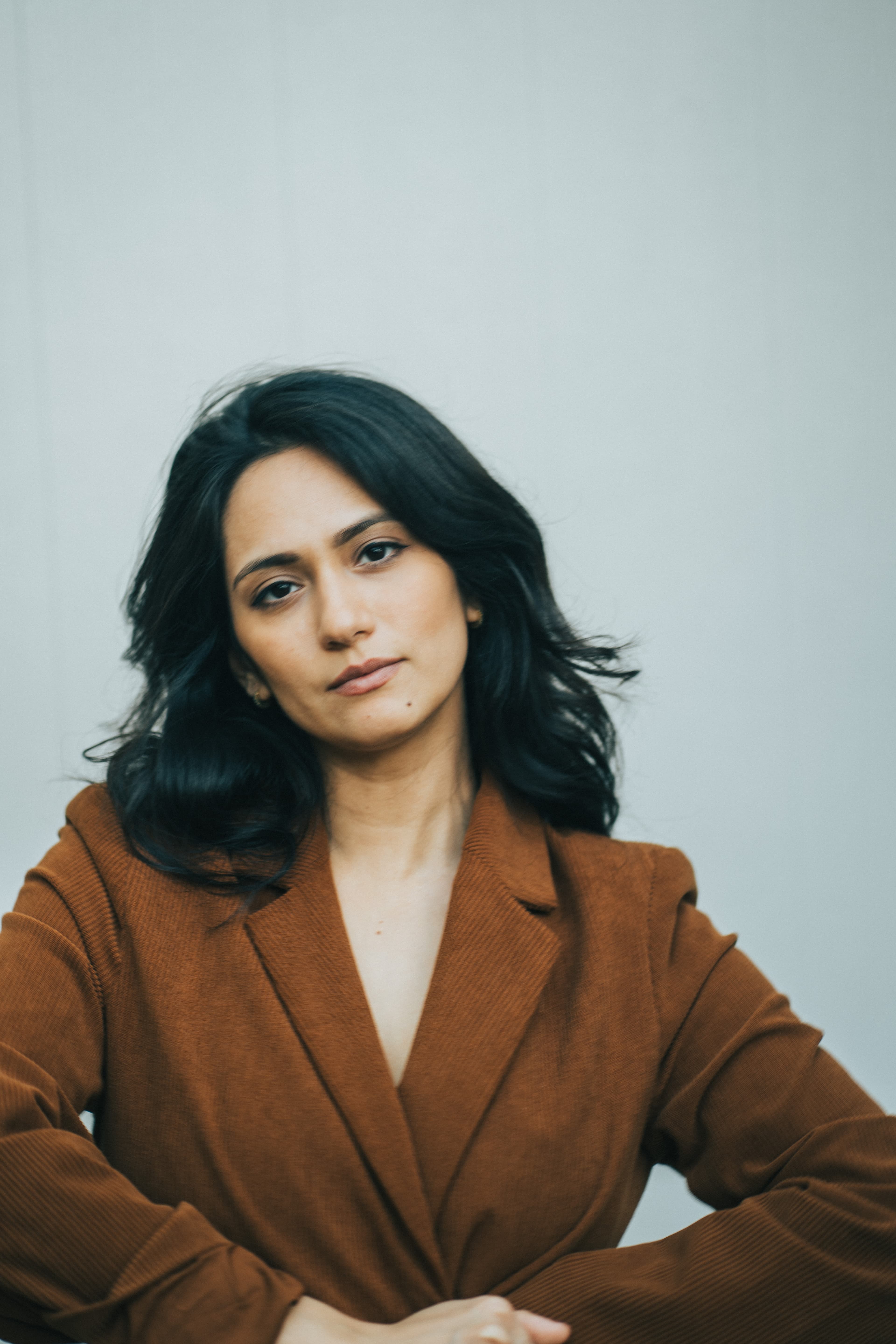 Portrait of Amberly Daniels seated in a rust blazer